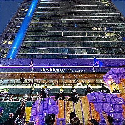 Hotel facade during a festive event with a parade float and spectators below